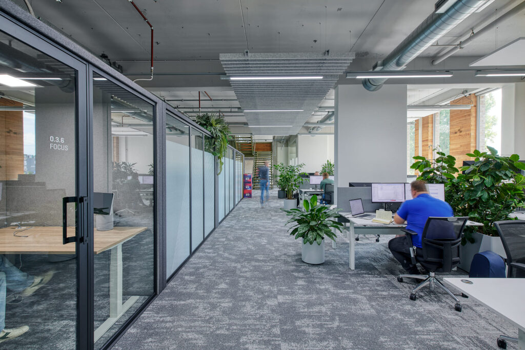Open kantoor met focusruimtes, planten en lineaire verlichting