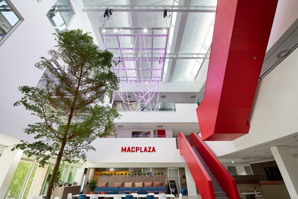 Het atrium Macplaza met rode trappen en een lichtkunstwerk